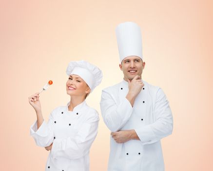 cooking, profession, teamwork, inspiration and people concept - happy chefs or cooks couple over beige background