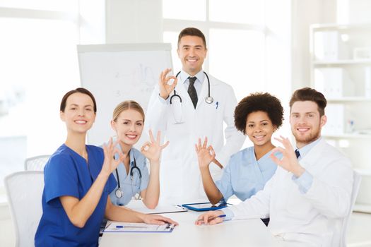 hospital, profession, medical education, people and medicine concept - group of happy doctors meeting on presentation or conference at hospital and showing ok hand sign