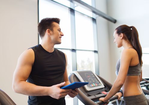sport, fitness, lifestyle, technology and people concept - happy woman with trainer working out on treadmill in gym