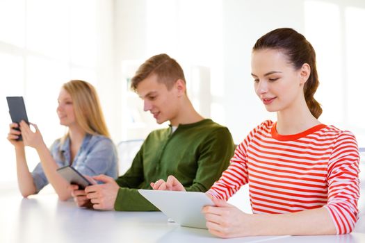 education, technology and internet concept - smiling students looking at tablet pc computer at school