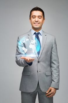 business, people, technology and global communication concept - happy businessman in suit showing globe hologram over gray background