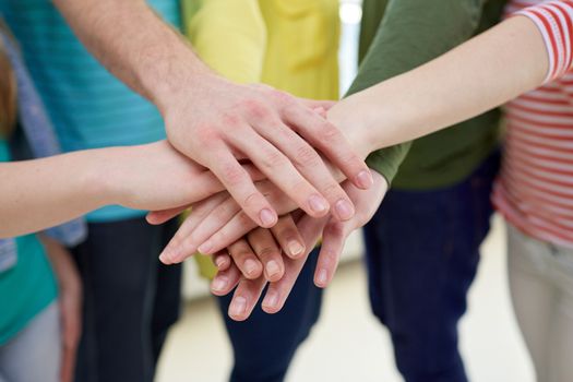 education, school, people, friendship and teamwork concept - close up of students or friends with hands on top sitting on staircase