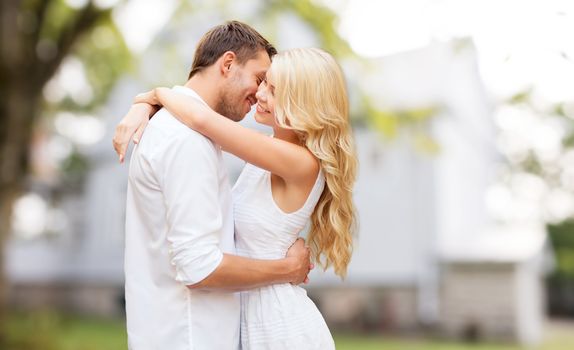 home, real estate, people, love and dating concept - happy couple hugging over summer house background