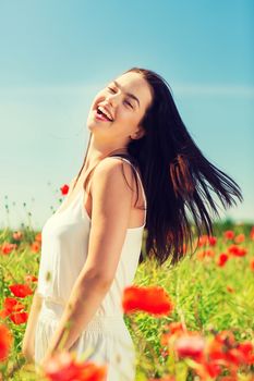 happiness, nature, summer, vacation and people concept - laughing young woman on poppy field