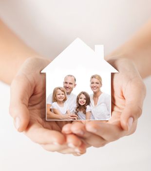 real estate, home insurance and happiness concept - close up of female hands holding white house with happy family picture