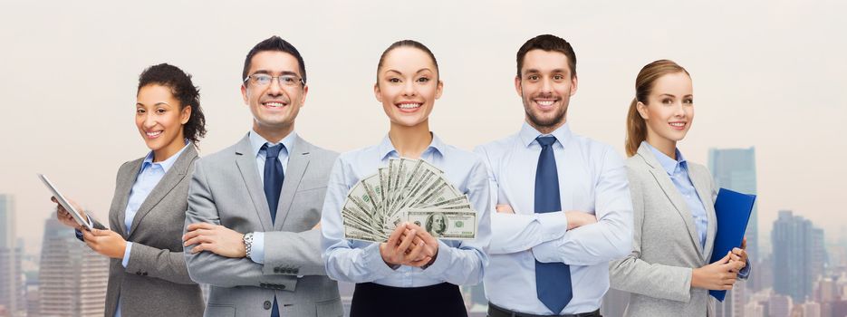 business, success and finances concept - group of smiling business people with dollar cash money over city background