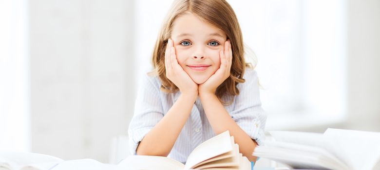 education and school concept - little student girl studying and reading books at school