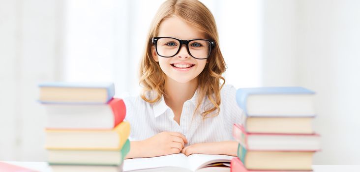 education and school concept - little student girl studying and reading books at school