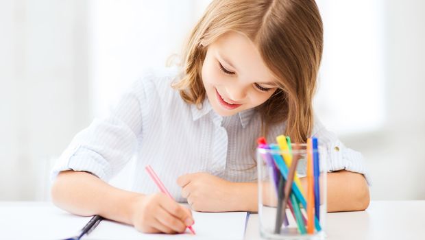 education and school concept - little student girl drawing at school