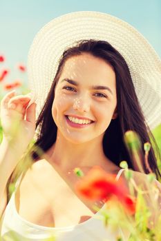 happiness, nature, summer, vacation and people concept - smiling young woman wearing straw hat on poppy field