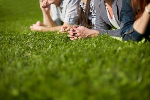 summer holidays, friendship, leisure and teenage concept - close up of students or teenagers lying on grass and hanging out at campus or park