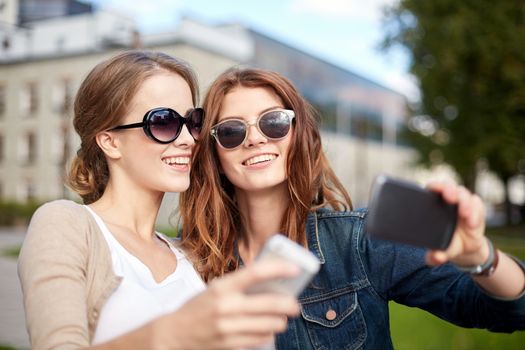 summer, technology, education and teenage concept - two happy students or teenage girls with smarphone taking selfie
