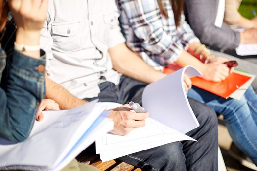 summer, friendship, education and teenage concept - close up of students with notebooks reading and writing at campus