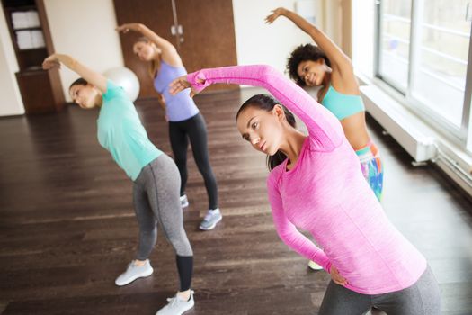 fitness, sport, training, gym and lifestyle concept - group of happy women working out and stretching in gym
