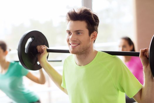 fitness, sport, training, gym and lifestyle concept - group of people exercising with barbell in gym