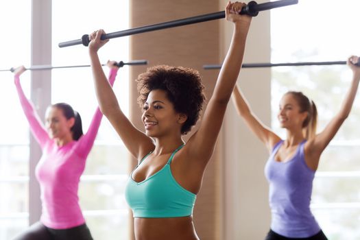 fitness, sport, training, gym and lifestyle concept - group of people exercising with bars in gym