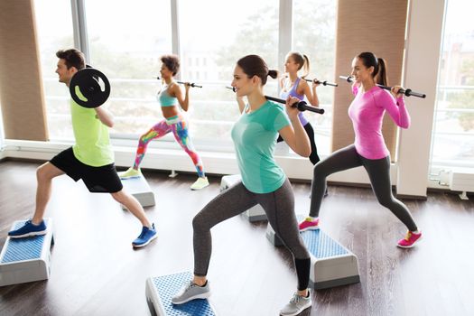 fitness, sport, training, gym and lifestyle concept - group of people exercising with barbell and bars in gym