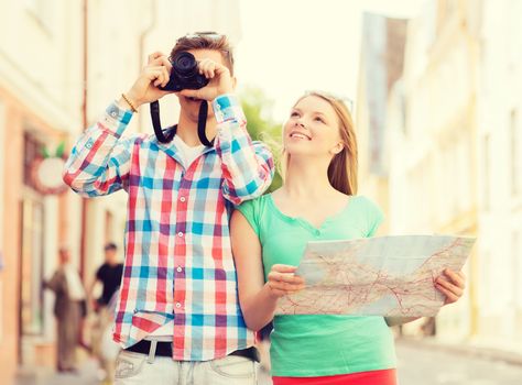 travel, vacation, technology and friendship concept - smiling couple with map and photo camera exploring city