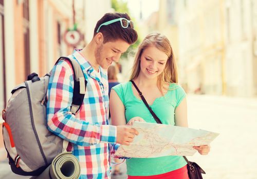 travel, vacation and friendship concept - smiling couple with map and backpack in city