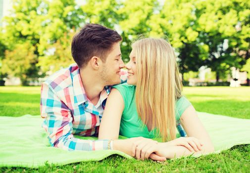 holidays, vacation, love and friendship concept - smiling couple lying on blanket in park