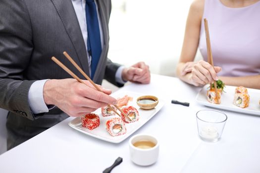 restaurant, food, people, date and holiday concept - close up of couple eating sushi at restaurant