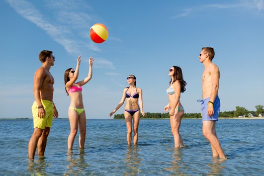 friendship, sea, summer vacation, holidays and people concept - group of smiling friends wearing swimwear and sunglasses talking on beach