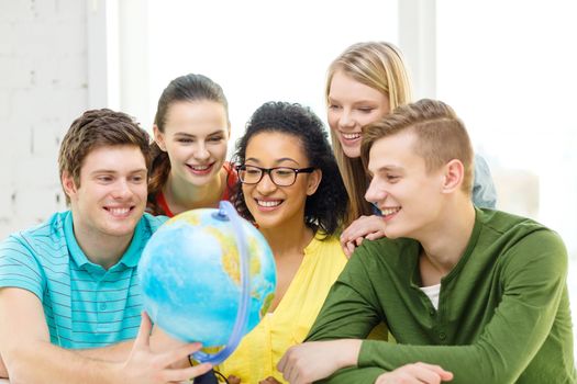 education, travel and geography concept - five smiling student looking at earth globe at school