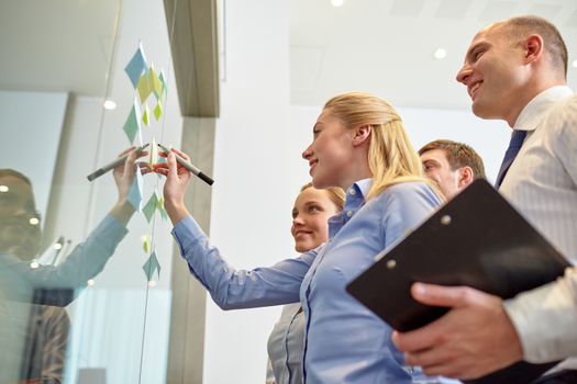 business, people, teamwork and planning concept - smiling business team with marker and stickers working in office