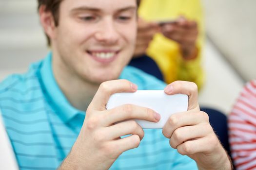 people, technology and internet concept - close up of young man with smartphone at school