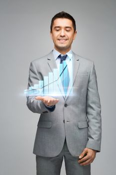 business, people, statistics and economics concept - happy businessman in suit showing or holding virtual chart projection on palm over gray background