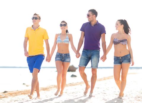 summer holidays, vacation, tourism, travel and people concept - group of happy friends holding hands and walking along beach