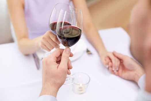 restaurant, people, celebration and holiday concept - close up of young couple with glasses of red wine at restaurant