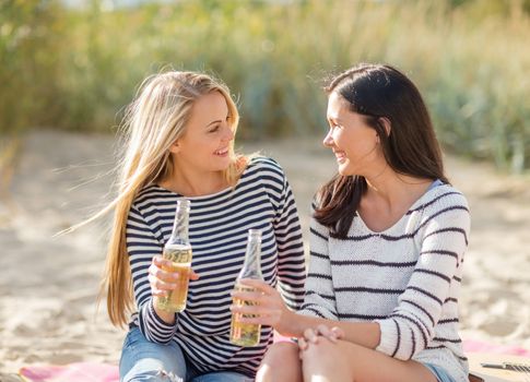 summer holidays, vacation, celebration and people concept - happy teenage girls or young women drinking beer or lemonade on beach