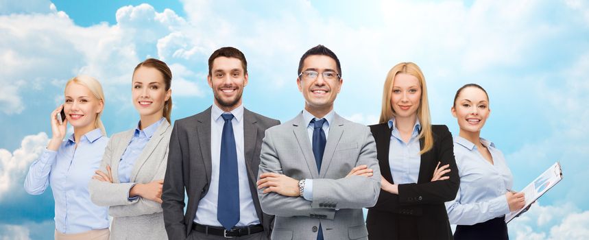 business, people, gesture and office concept - group of smiling businessmen over blue sky and clouds background