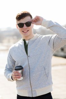 drinks and people concept - smiling young man or teenage boy drinking coffee from paper cup outdoors