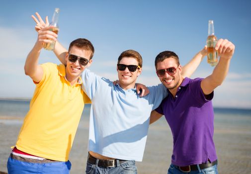 summer holidays, vacation, people and bachelor party concept - group of happy male friends having fun and drinking beer on beach