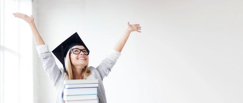 education concept - picture of happy student in graduation cap with stack of books