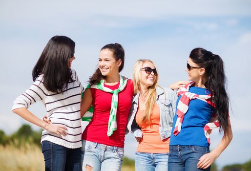 summer holidays, vacation and people concept - happy teenage girls in sunglasses or young women talking on beach