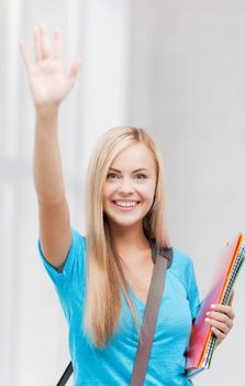 picture of smiling student with folders waving her hand