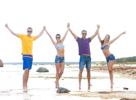 summer holidays, vacation, tourism, travel and people concept - group of happy friends holding hands on beach