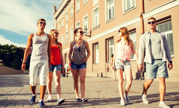 friendship, travel, tourism, summer vacation and people concept - group of smiling teenagers walking in the city