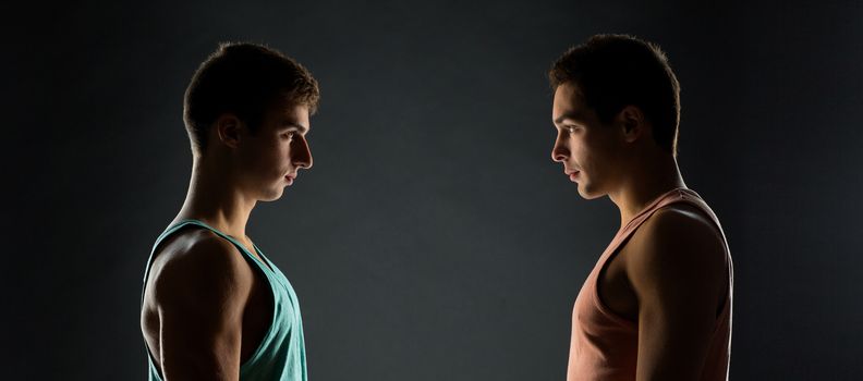sport, bodybuilding, competition and people concept - young men looking to each other