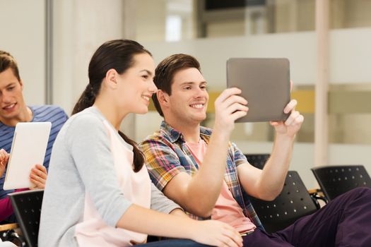 education, high school, teamwork and people concept - group of smiling students with tablet pc computers making photo or video in lecture hall