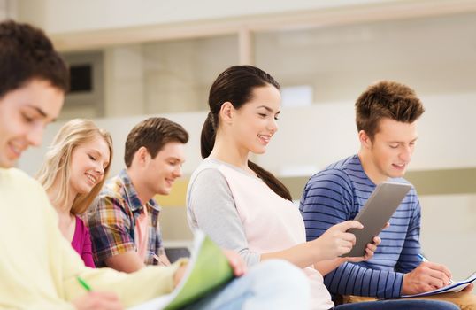 education, high school, teamwork and people concept - group of smiling students with tablet pc computer and notebooks sitting in lecture hall