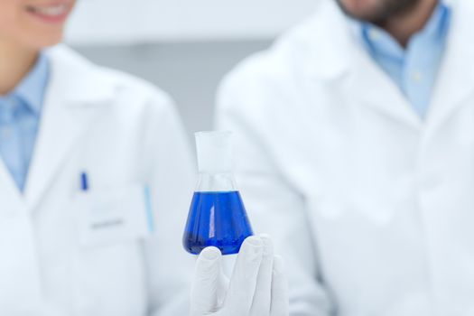 science, chemistry, biology, medicine and people concept - close up of scientists with test tube or glass flask making test or research in clinical laboratory