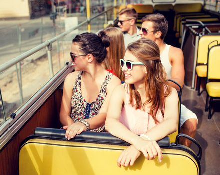 friendship, travel, vacation, summer and people concept - group of smiling friends traveling by tour bus