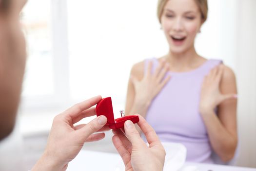 couple, love, engagement and holiday concept - close up of excited young woman and boyfriend giving her ring at restaurant