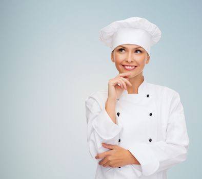 cooking and food concept - smiling female chef, cook or baker dreaming over gray background