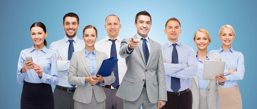 business, people, corporate, teamwork and office concept - group of happy businesspeople pointing at you over blue background