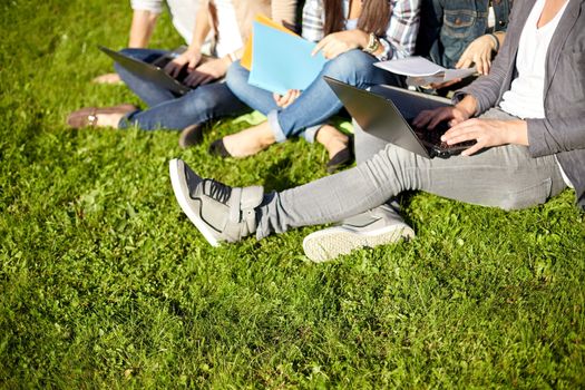 summer, education, campus, people and teenage concept - close up of students with laptop computers and folders sitting on grass